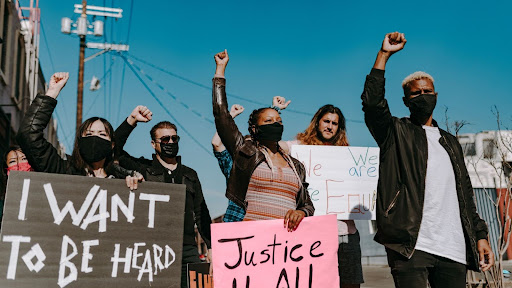 A group of multicultural Gen Z protestors holding signs and speaking out against injustice