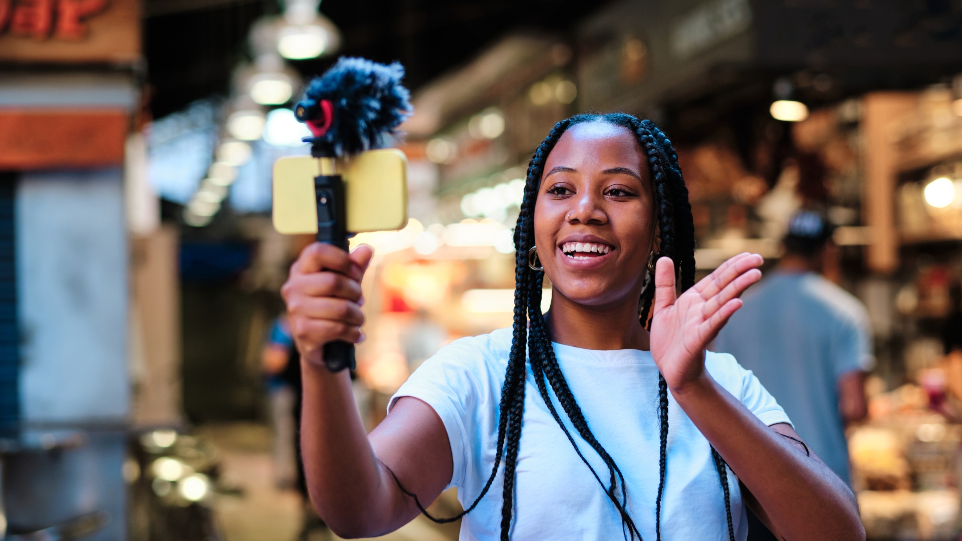 Gen Z woman of color with braids and wearing a white top creating user generated content on behalf of a brand