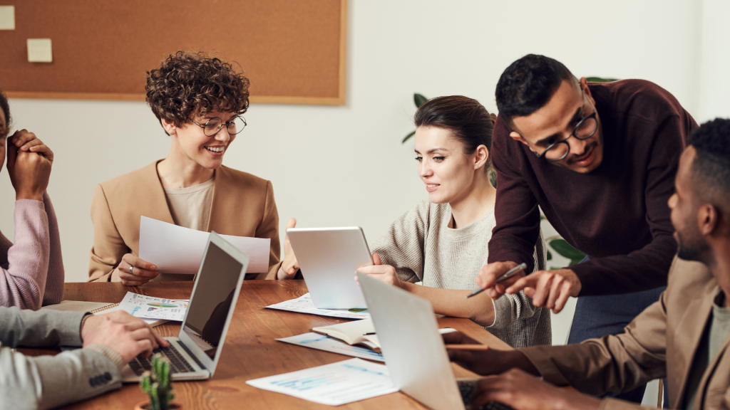 Diverse team sits around board room table reflecting on previous campaigns to avoid making unnecessary missteps.