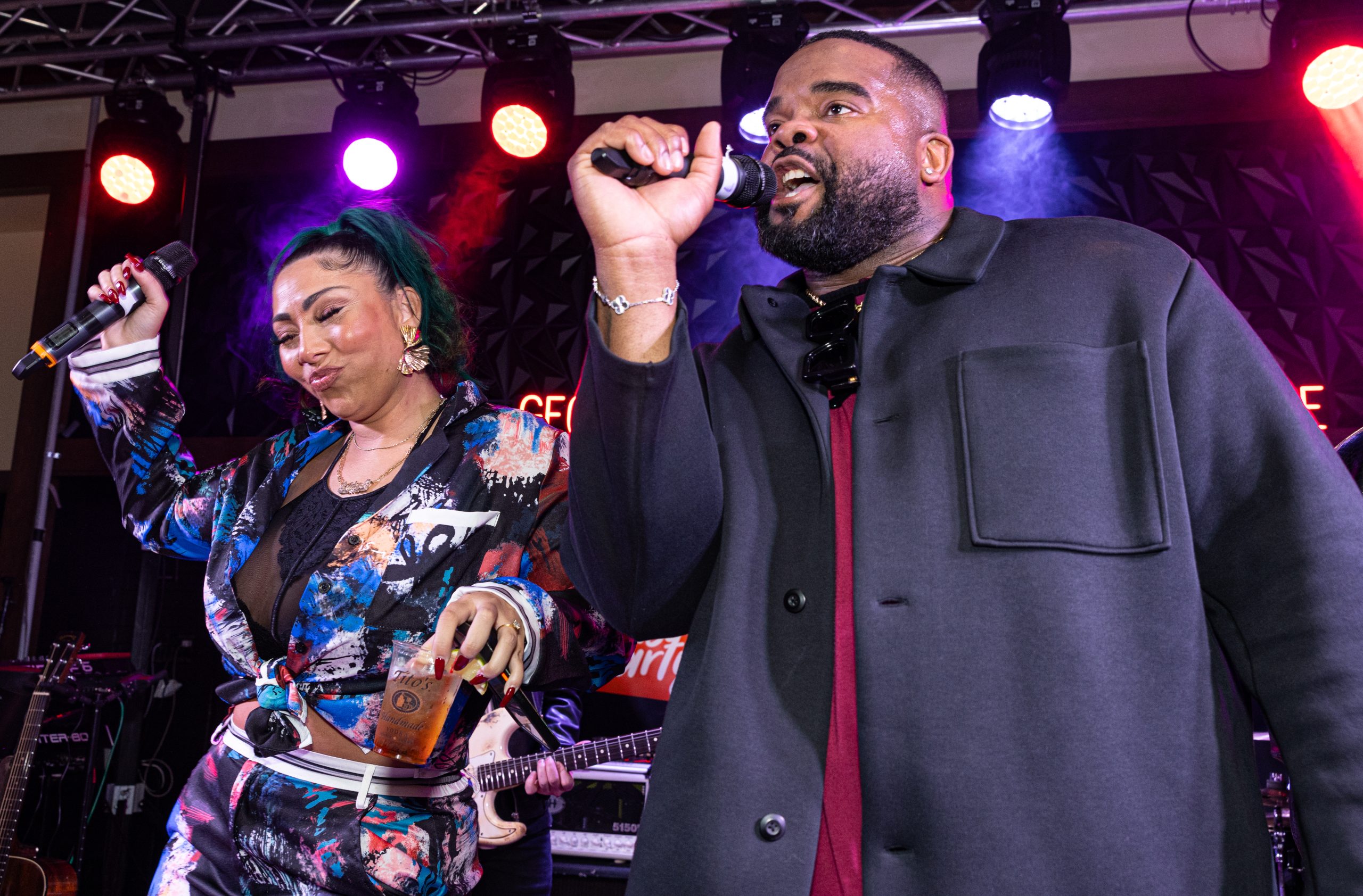 Event host, Charles Kuykendoll, on stage at the Georgia Street Rhythm & Blues Lounge with Bridget Kelly holding a microphone speaking to the audience.