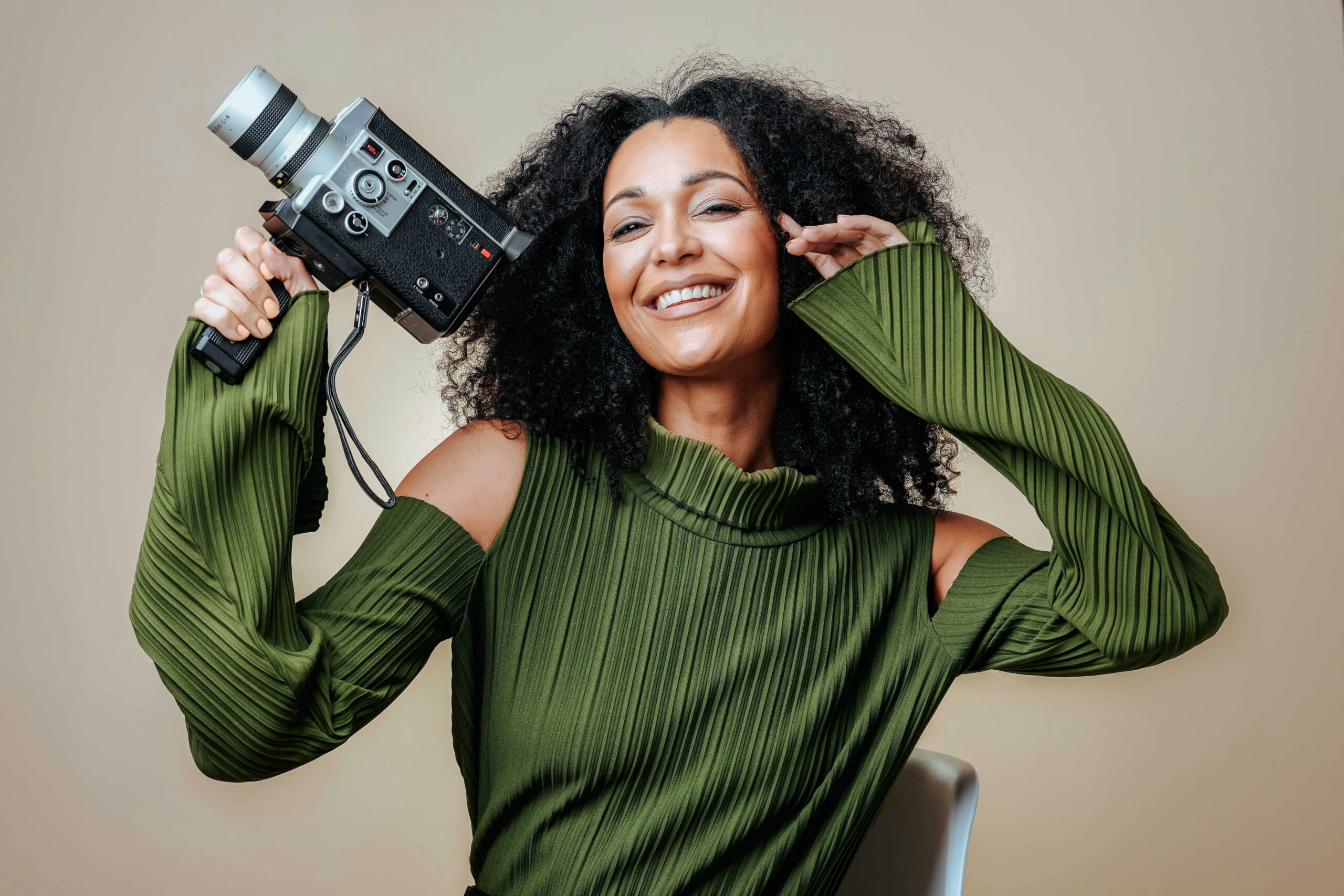 A smiling content creator holding a vintage video camera, showcasing creativity and passion in the creator economy.
